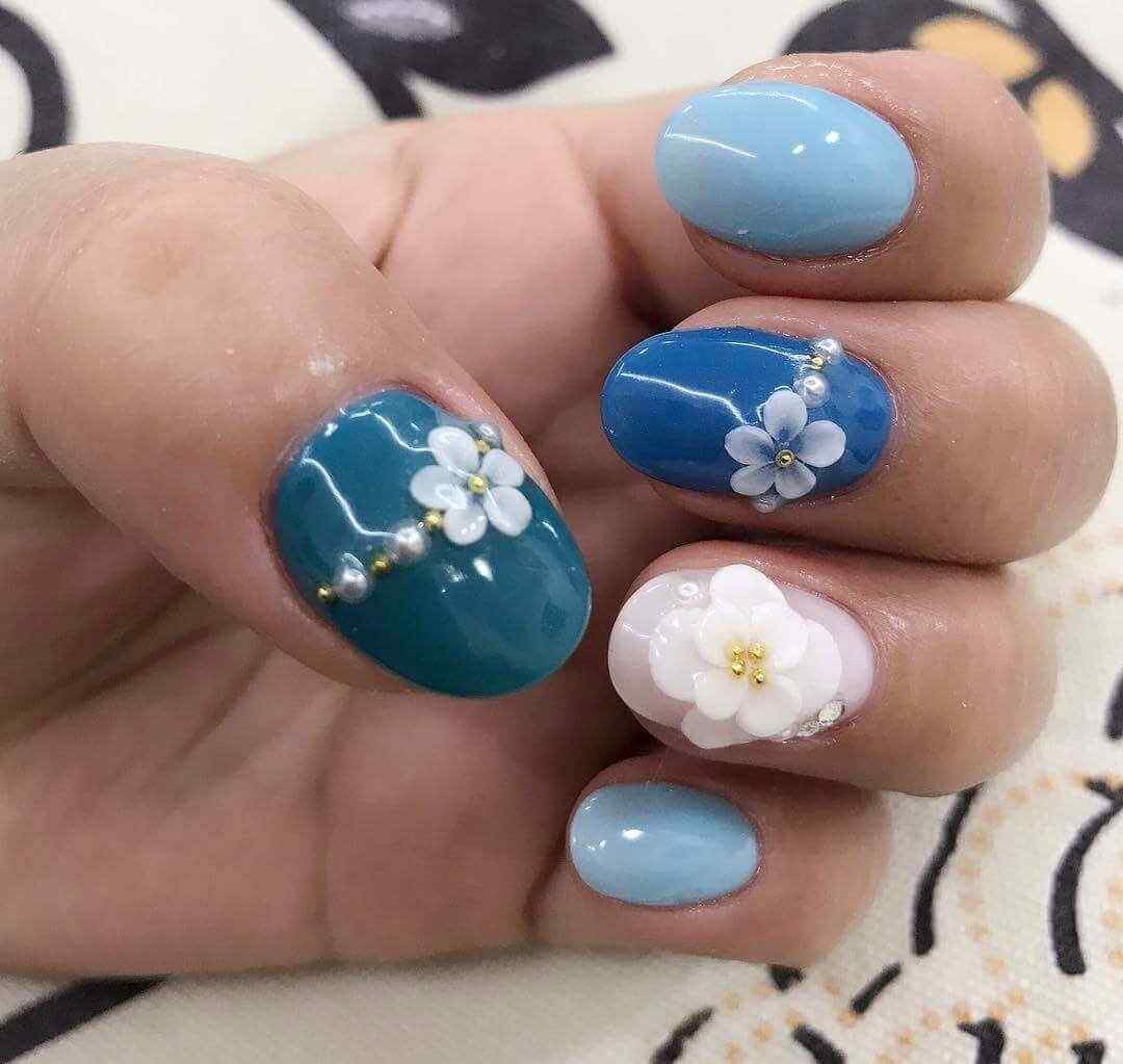 uñas celestes con flores blancas
